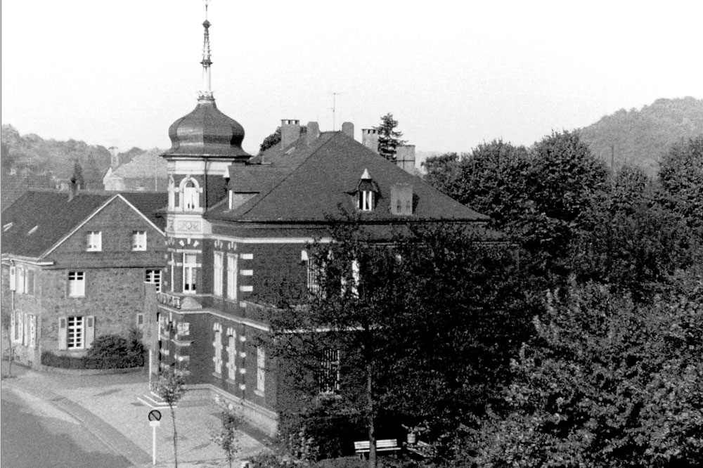 Historische Aufnahme. Links: alte Ortsschule, daneben Rathaus (von 1892 bis 1920), ab 1928 (1924 ?) Haus der Sparkasse bis 1987. (c) H.-W. Mekus, Repro